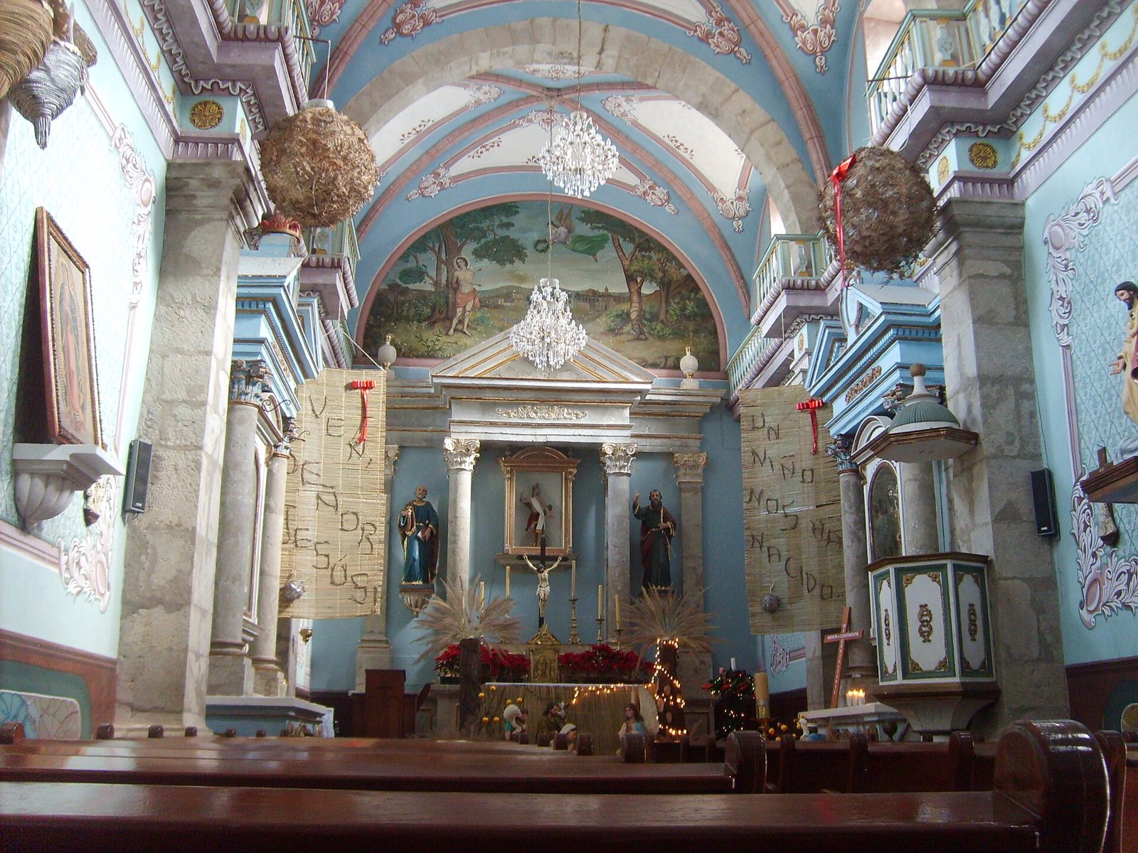Interior de la parroquia de San Sebastián con bóveda pintada, candiles y retablo principal