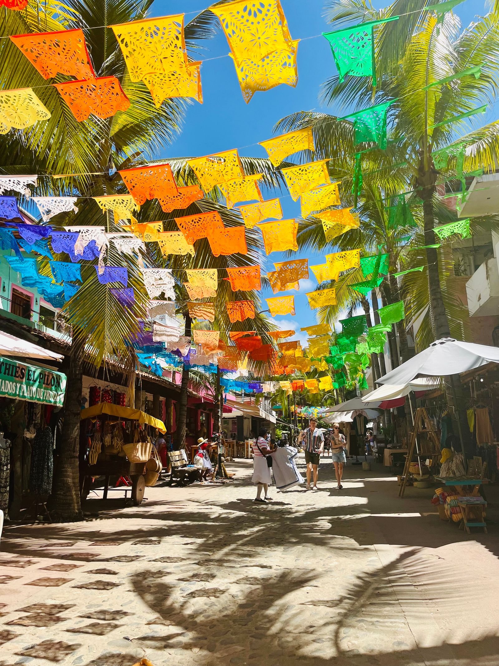 Calle peatonal de Sayulita adornada con papel picado de colores y palmeras