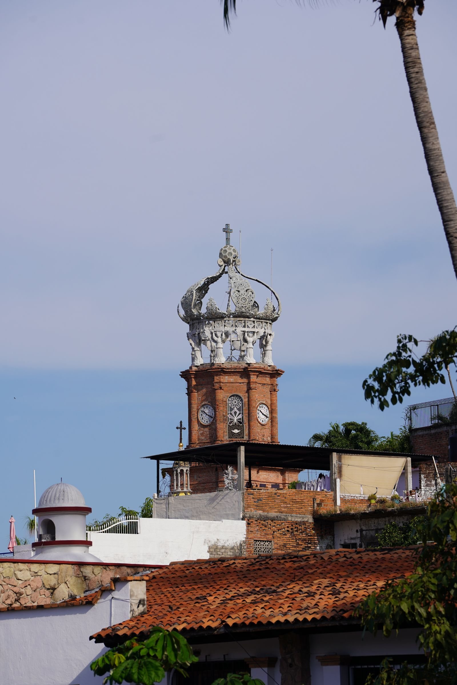 Torre de ladrillo con reloj y corona blanca de la Parroquia de Guadalupe sobre los techos de teja del centro