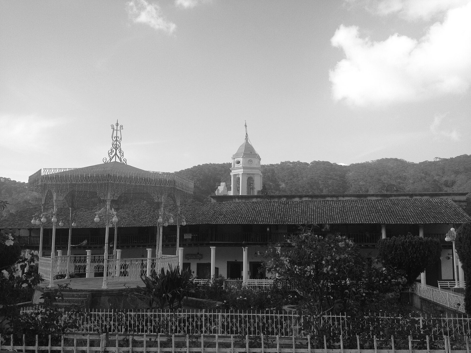 Foto en blanco y negro de la plaza de San Sebastián del Oeste con su kiosco, portales y la torre del templo