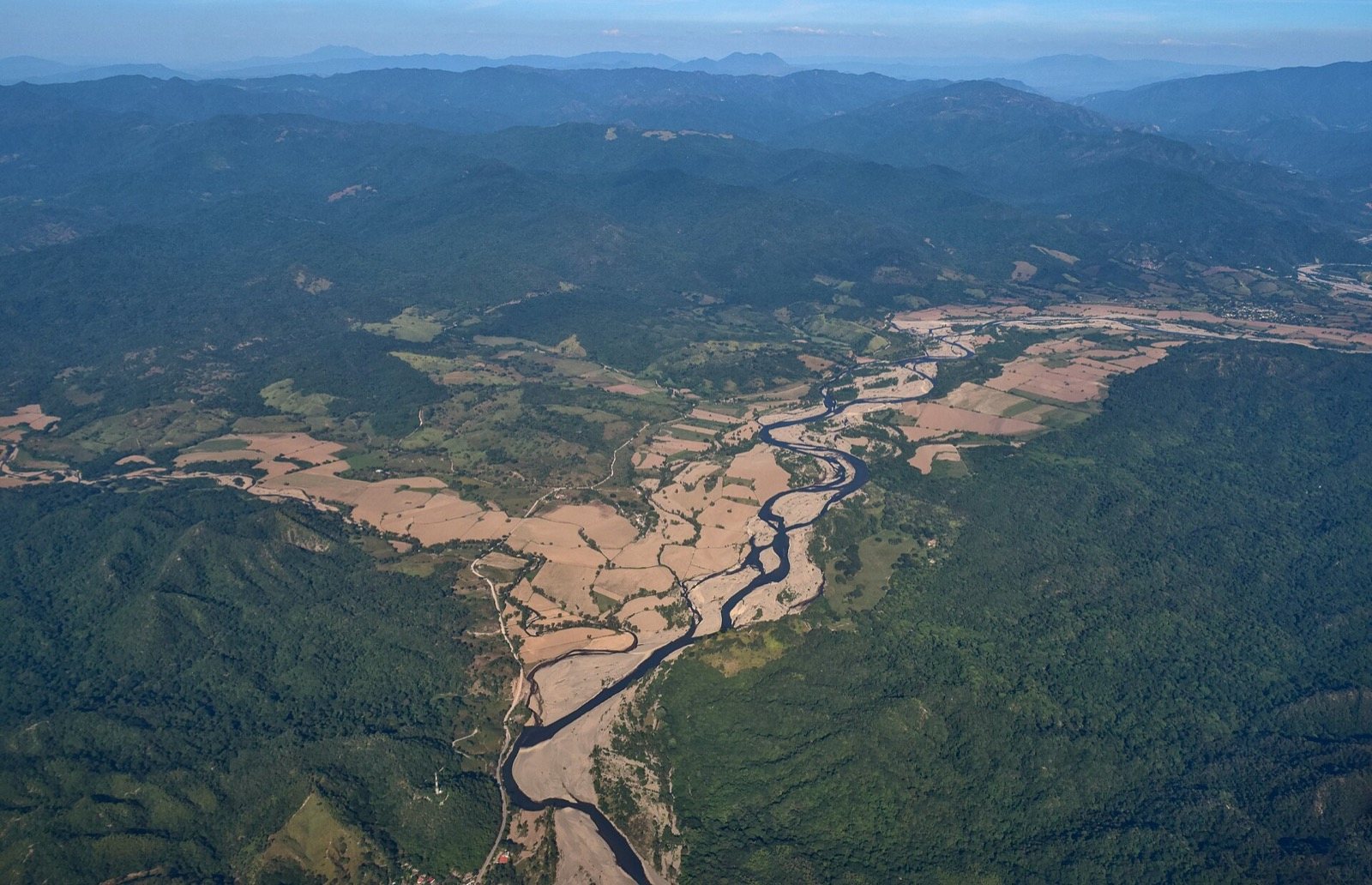 Vista aérea del río Ameca serpenteando entre campos de cultivo y montañas cubiertas de selva