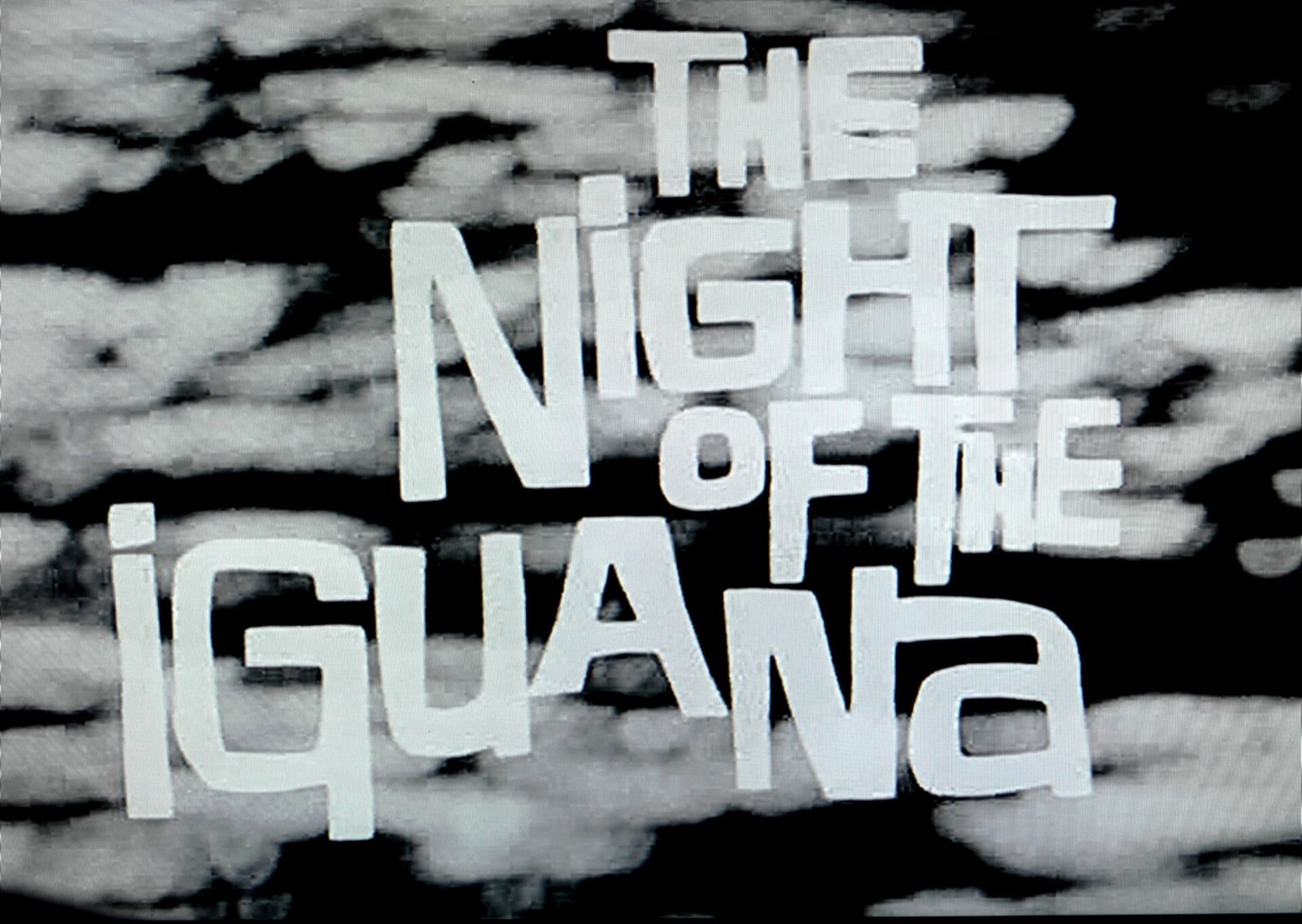 Título de la película The Night of the Iguana en letras blancas sobre fondo en blanco y negro