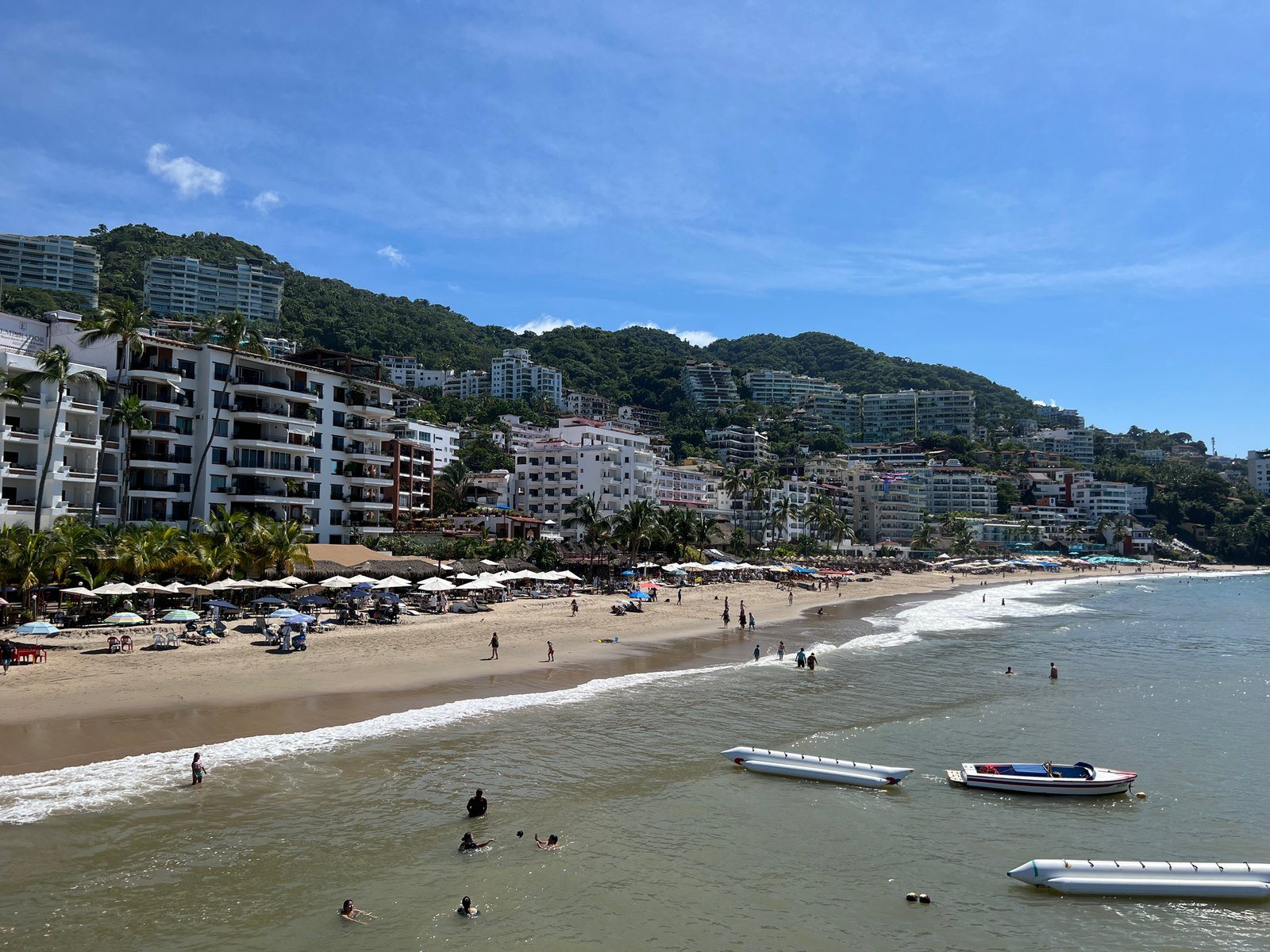 Playa Los Muertos vista desde el muelle, con edificios y cerros verdes al fondo