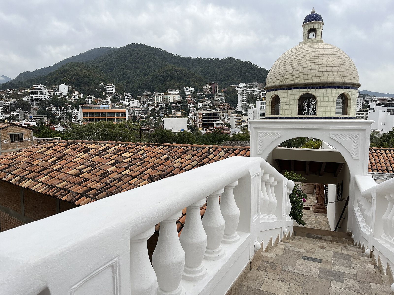 Vista desde el puente de Casa Kimberly con balaustrada blanca, cúpula y los cerros de Puerto Vallarta al fondo