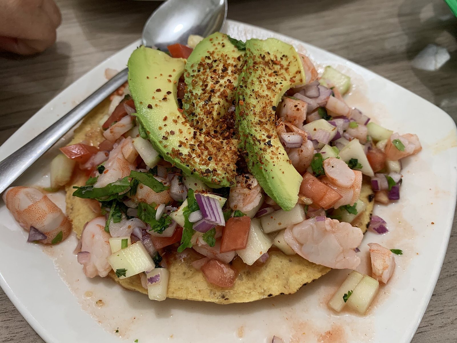 Tostada de ceviche de camarón con jitomate, pepino, cebolla morada, cilantro y rebanadas de aguacate con chile en polvo