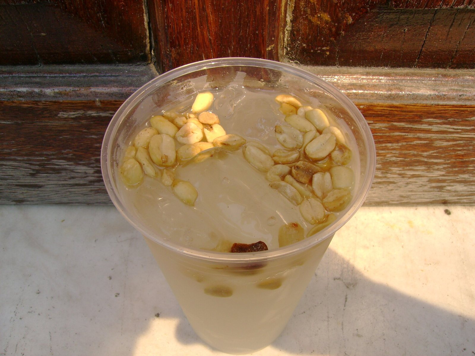Vaso de tuba con hielo y cacahuates encima, visto desde arriba